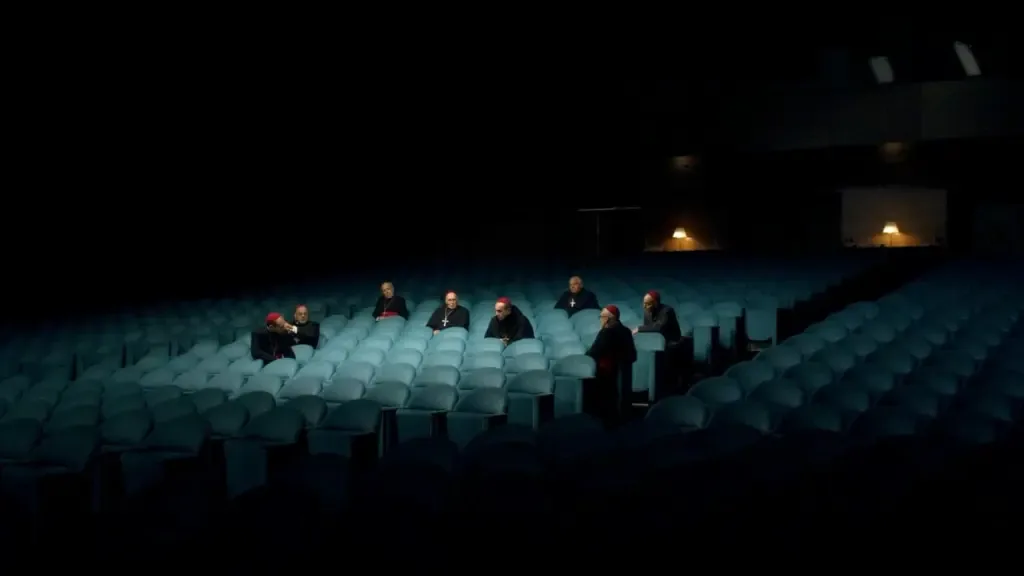 Figures seated in a dark, empty theater